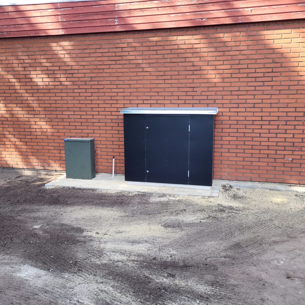 Det nye sorte skab med fjernvarmeinstallationen op ad murstensvæggen